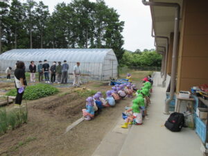 園児が横一列に並んでいる前で福田先生が話をしています